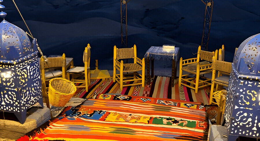 Dinner table laid out at a camp in the Agafay desert at dusk, with the High Atlas behind