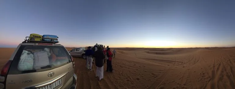 Sunrise over the Merzouga Sahara with 4x4 vehicles