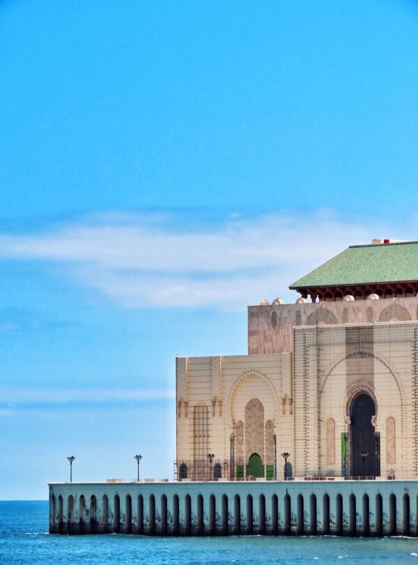 The Hassan II Mosque in Casablanca seen from the Atlantic seafront, its minaret rising above the ocean wall