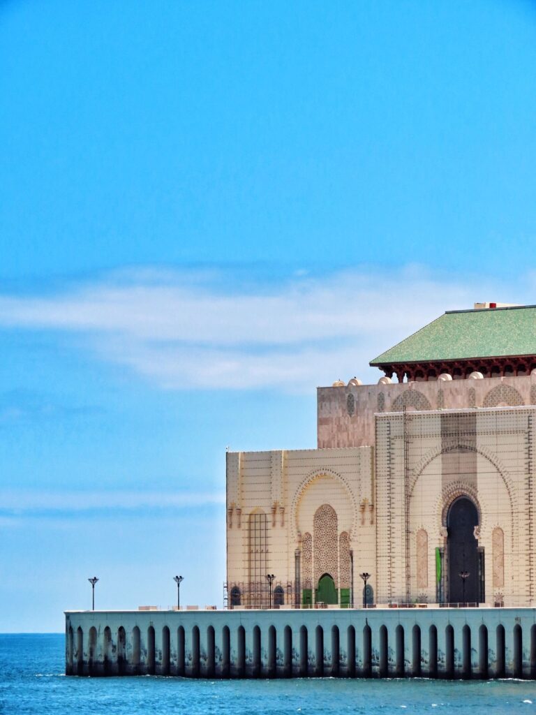 The Hassan II Mosque in Casablanca seen from the Atlantic seafront, its minaret rising above the ocean wall