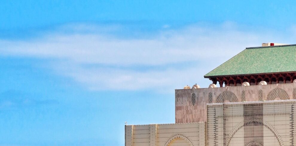 The Hassan II Mosque in Casablanca seen from the Atlantic seafront, its minaret rising above the ocean wall